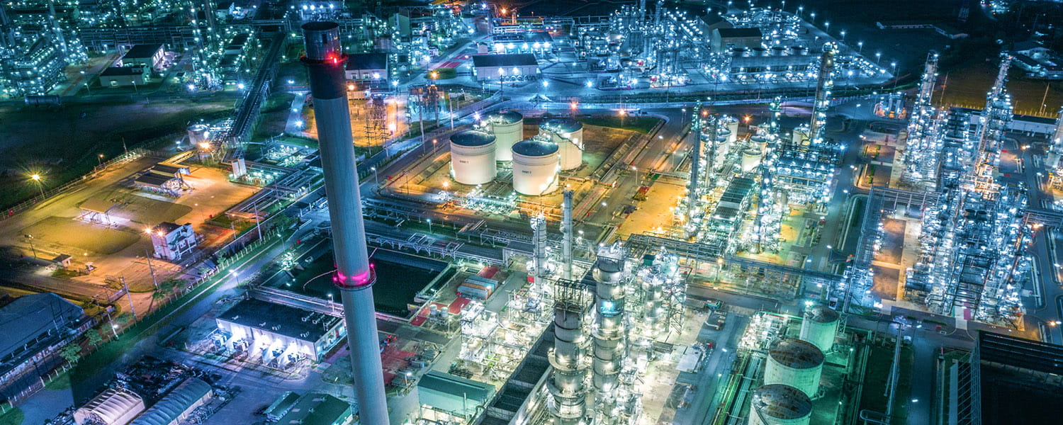 Aerial view of a petrochemical plant at night, with lots of bright lights. 