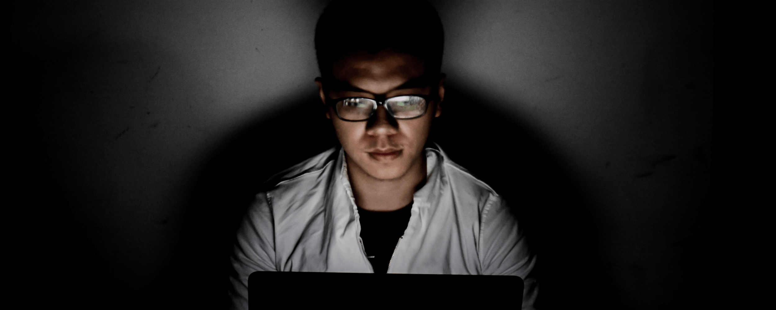Man on computer in dark room