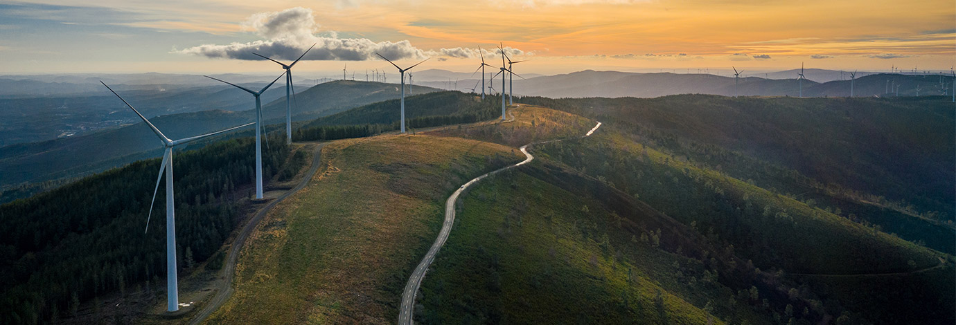 Wind turbines on a mountain top with a path running alongside.