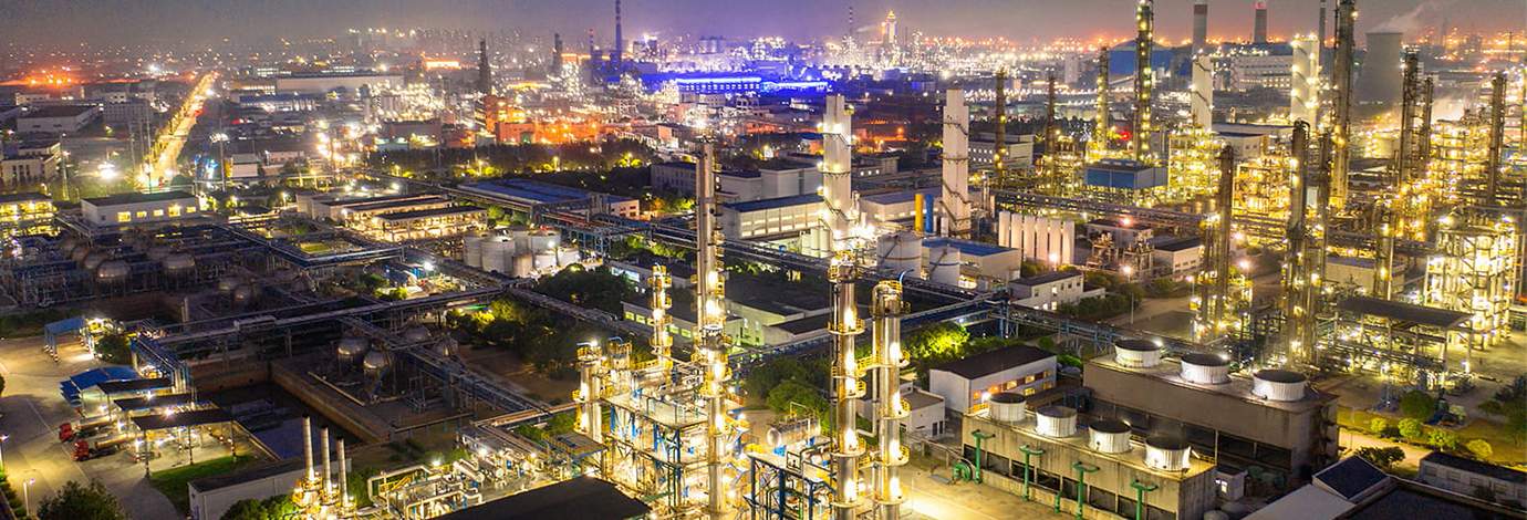 Aerial view of an oil refinery with lights on at night.