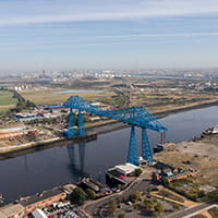 Aerial view of a blue transporter bridge over the Tees River in Middlesborough.