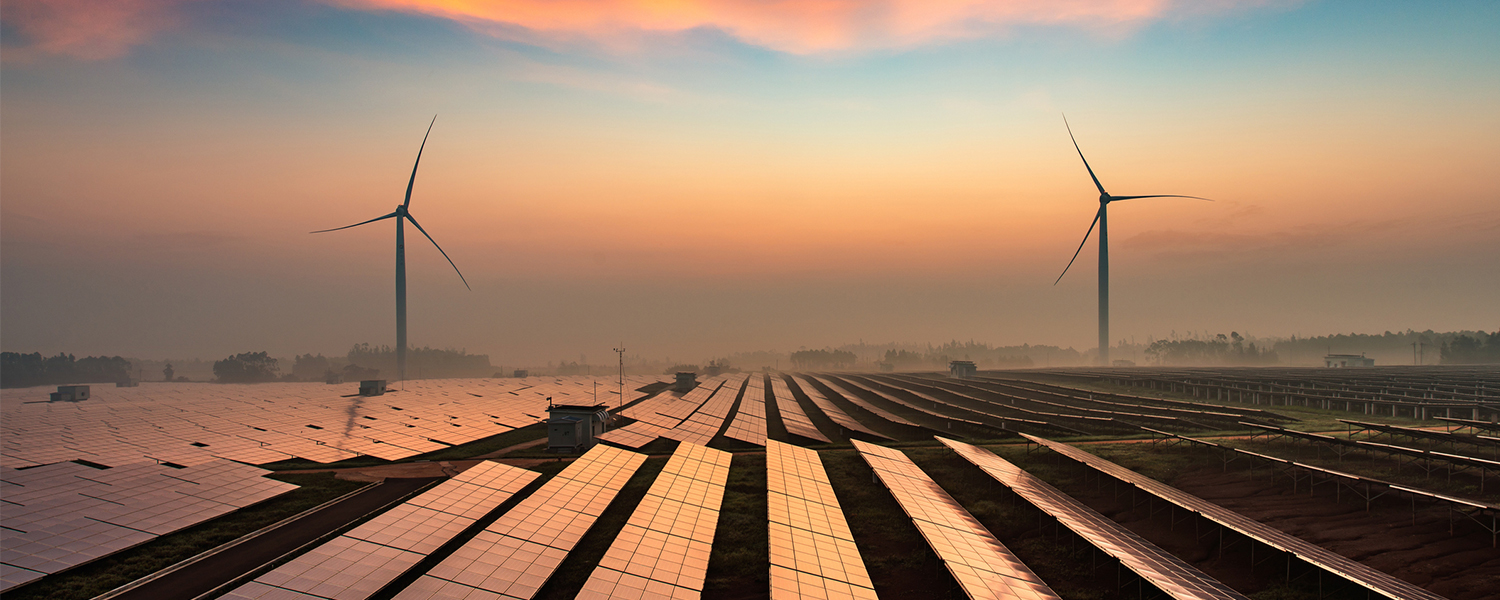 Solar panels and wind turbines creating energy at twilight